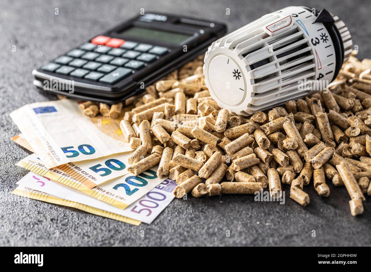 Ökologische Heizung. Holzpellets, Euro-Banknoten, Taschenrechner und Thermostat-Kopf. Stockfoto