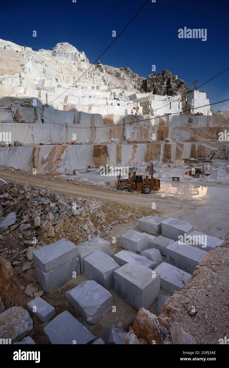 Carrara-Marmorbrüche, viereckige weiße Marmorblöcke auf dem Steinbruch von Gioia, Bulldozer, Maschinen, Bagger, Massa-Carrara, Lunigiana, Toskana, Italien Stockfoto