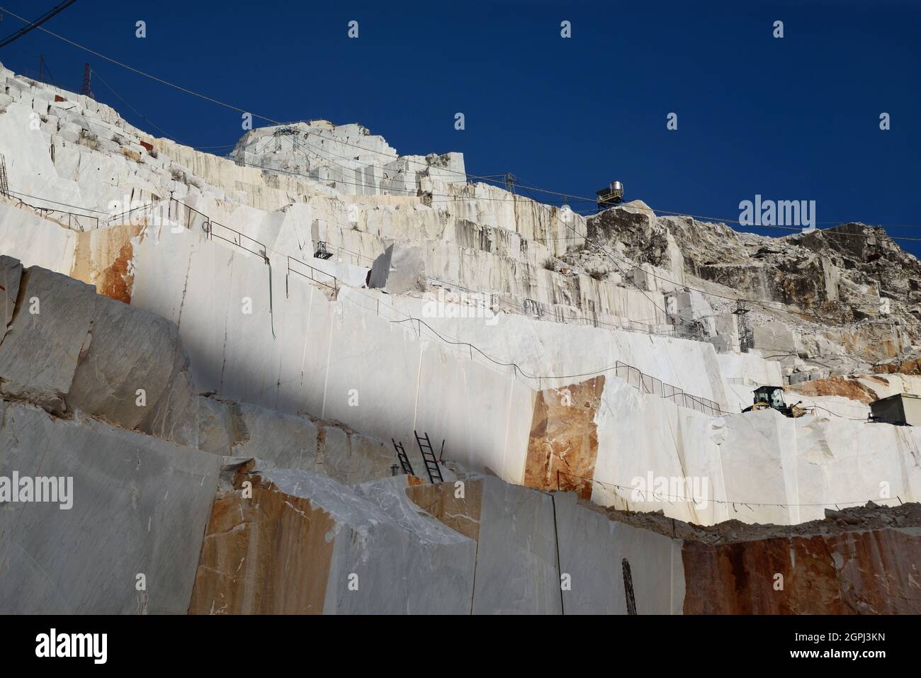 Carrara-Marmorbrüche, viereckige weiße Marmorblöcke auf dem Steinbruch von Gioia, Bulldozer ...