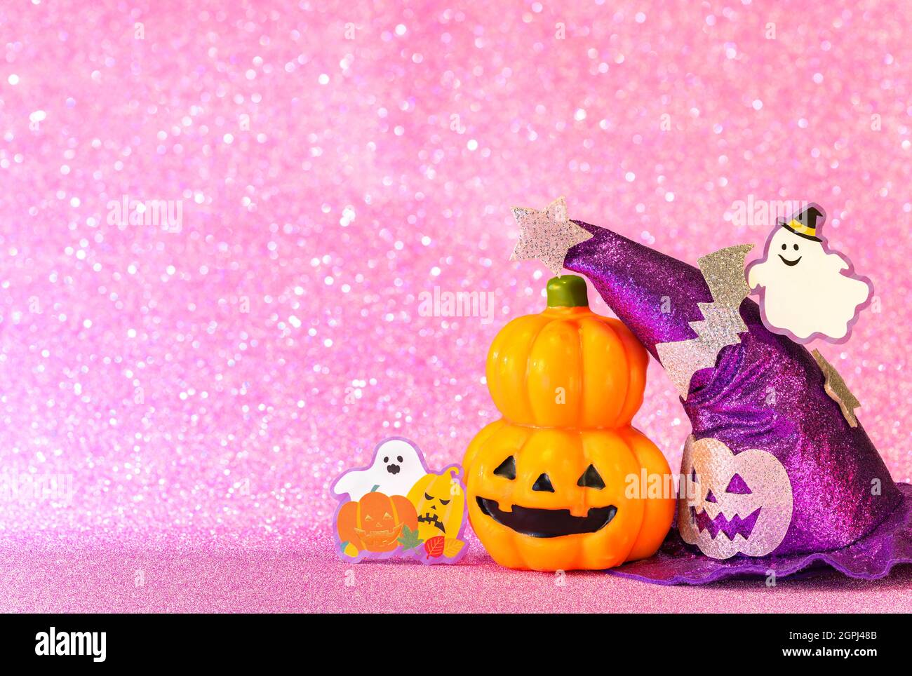 Konzeptfotografie mit einem halloween Jack o Laterne Kürbis Kopf und einem lila Hexenhut mit lustigen Geist lächeln und Karton Ausschnitt Fledermäuse aga Stockfoto