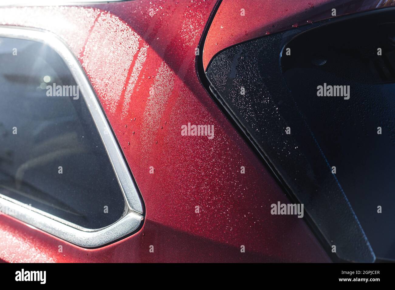 Leuchtendes rotes Metallic-Auto mit Regentropfen, Nahaufnahme mit selektivem Fokus Stockfoto