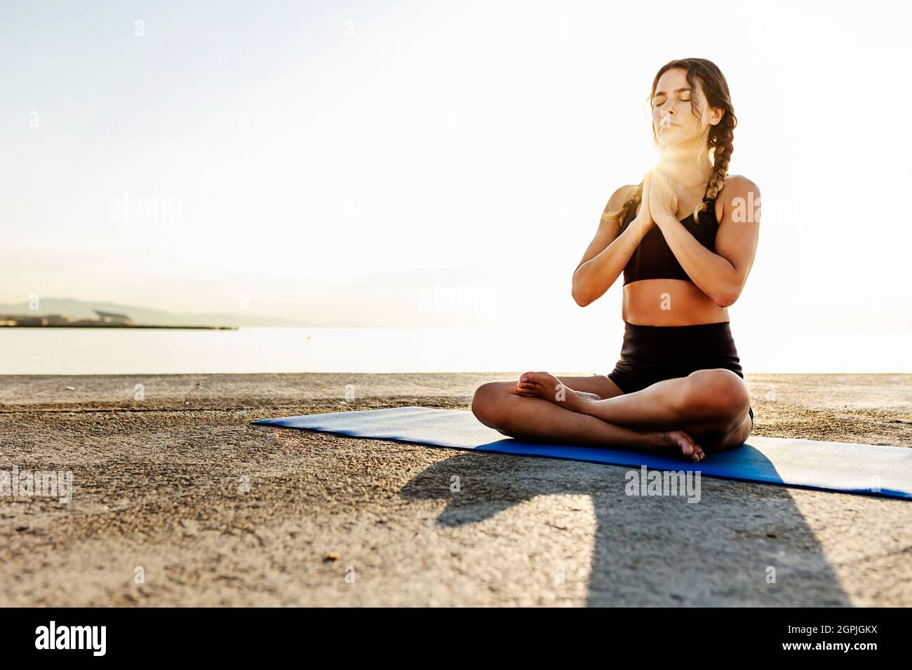 Entspannte hispanische junge Frau mit geschlossenen Augen meditiert und praktiziert Yoga Stockfoto