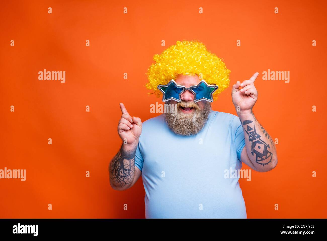 Fat glücklicher Mann mit Bart, Tattoos und Sonnenbrillen tanzt Musik auf einer Disco Stockfoto