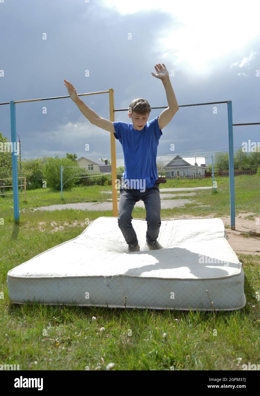 Kovrov, Russland. 11. Juni 2017. Teenager, die in Disziplin Gimbarr auf einer horizontalen Bar im Schulhof beschäftigt sind, führt Trick und landet auf der alten Matte Stockfoto