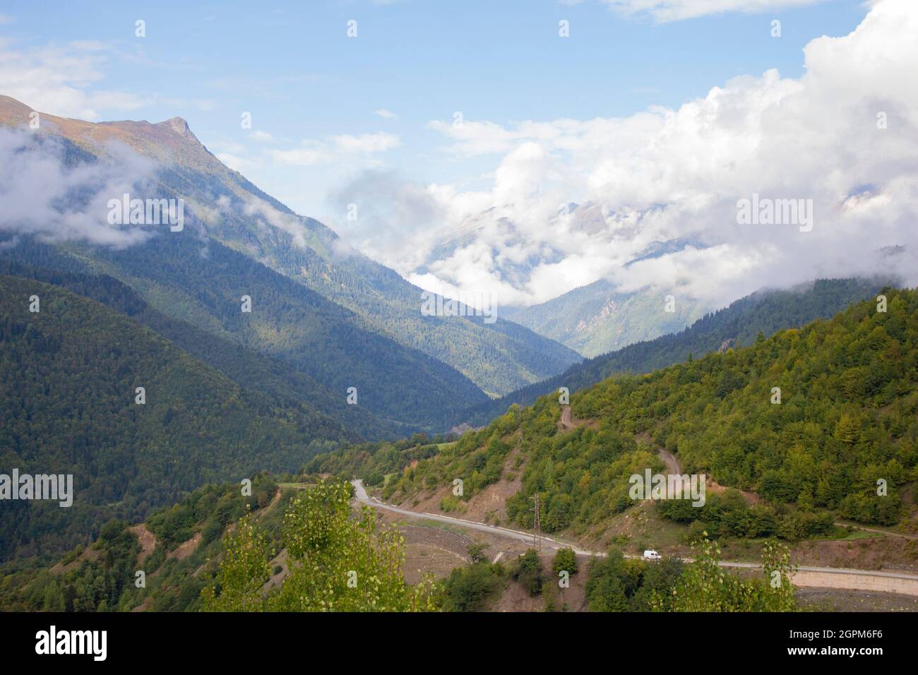 Sommer Berglandschaft in den Kaukasus-Bergen. Bergstraße. Grüner Wald. Blauer Himmel mit Wolken über den Gipfeln der Berge. Ein Tourist Stockfoto