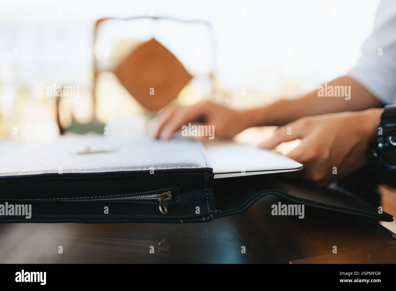 Hand, die den Laptop aus der Laptoptasche auf dem Tisch zieht. Stockfoto