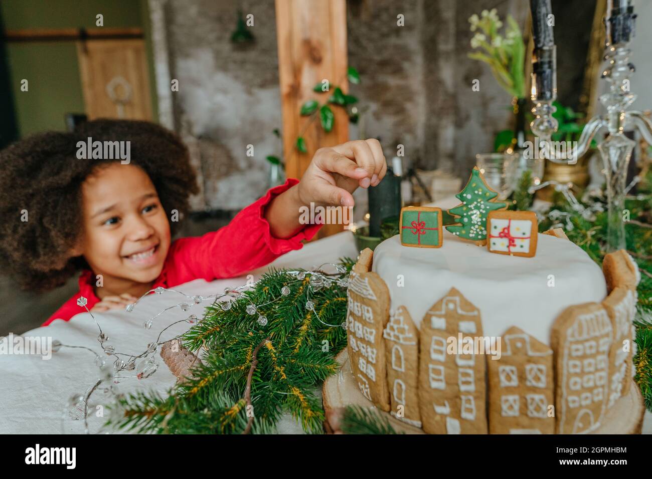 Mädchen, die Lebkuchen aus Weihnachtskuchen mit handgefertigten Haus Lebkuchen dekoriert. Idee für diy handgemachte Happy New Year festliche Süßigkeiten. Selektiv Stockfoto