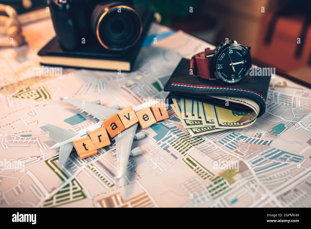 Holzquadrat mit Wort „Reise“, Uhr, Geldbörse, Reisepass, Flugzeugmodell, Kamera auf der Straßenkarte. Objekt für Reisekonzept. Stockfoto