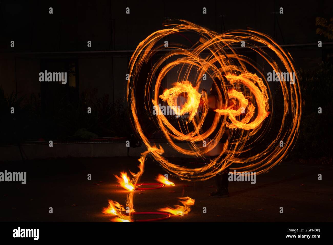 Straßenkünstler jongliert mit brennendem Hula Hoop bei einer Feueraufführung. Langzeitbelichtung Bild der abstrakten Feuer Licht Malerei. Stockfoto