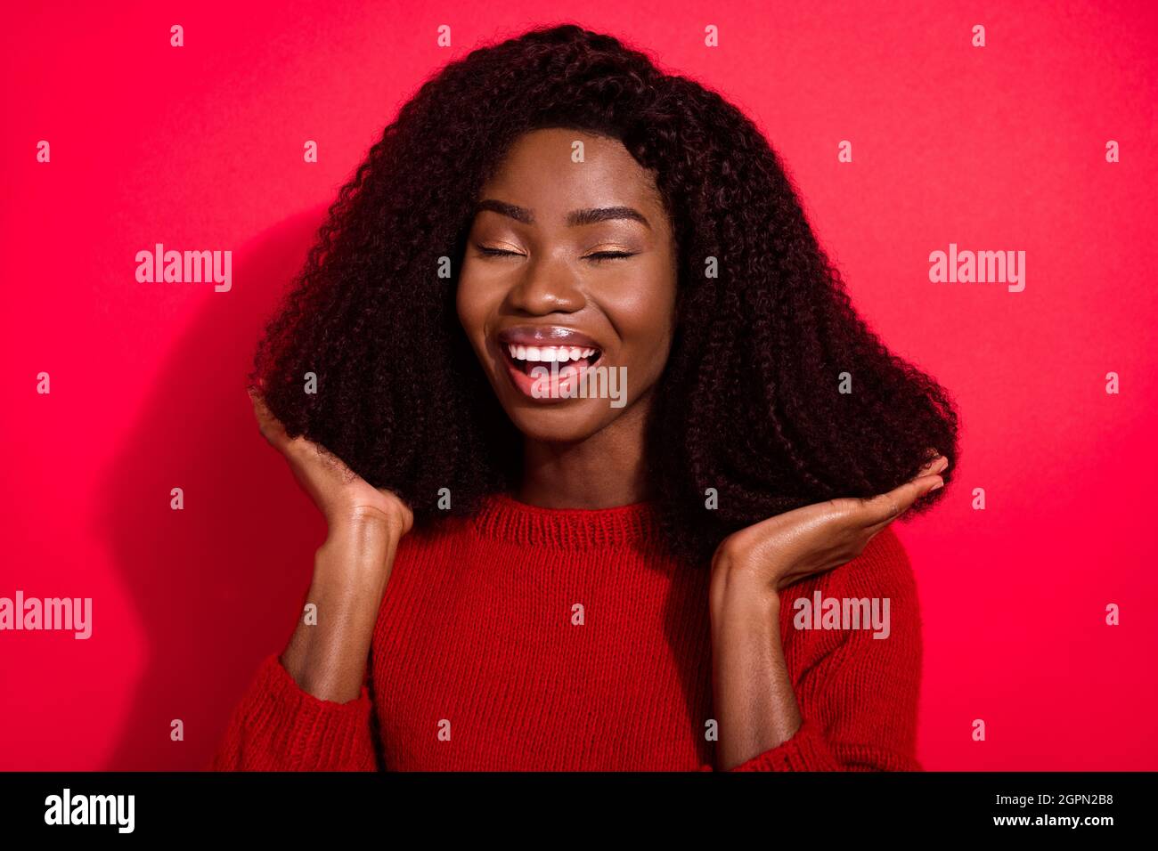 Foto von jungen afro Mädchen glücklich positive Lächeln Hand berühren neue Frisur Salon isoliert über roten Hintergrund Stockfoto