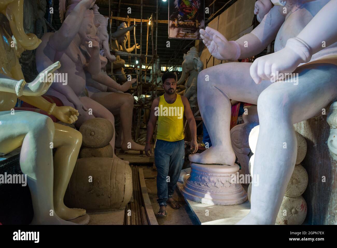 Ein Mann, der vor dem verheißungsvollen indischen Fest von Ganesh Chaturtha bei einem Workshop in Mumbai zwischen Statuen von Lord Ganesha spazierend ist Stockfoto