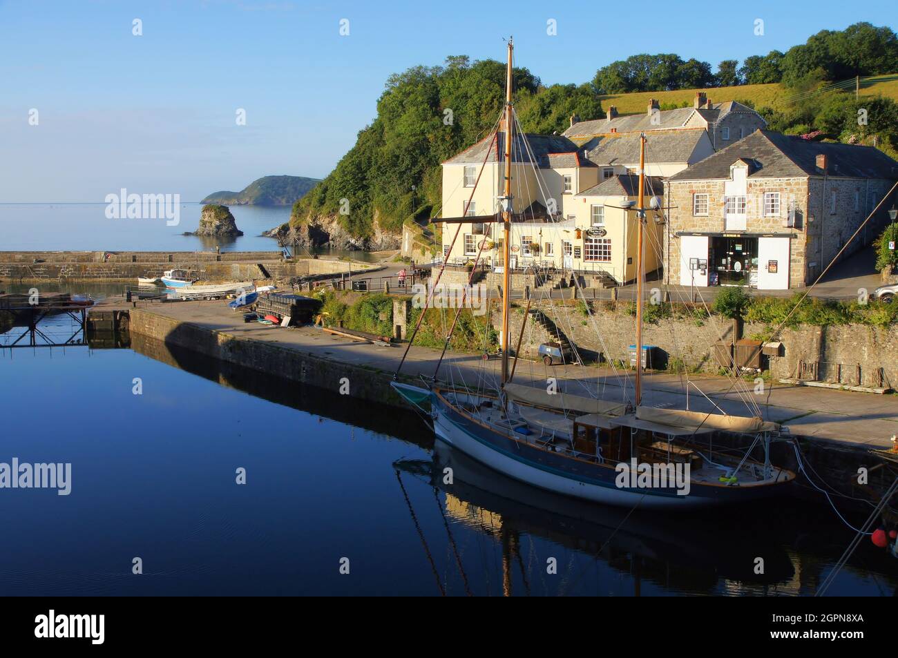 Dead Calm English Channel und Hafen mit Gebäuden und Hochschiff kurz nach Sonnenaufgang im Hafen von Charlestown, Cornwall, England Stockfoto