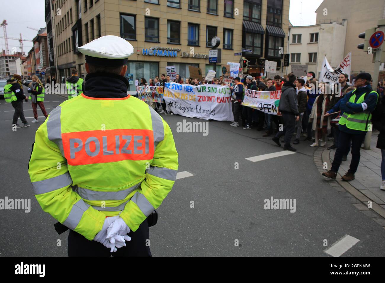 Ein Polizist steht Wache, während junge Demonstranten an einer Demonstration in Nürnberg im Rahmen der Studentenfreitags-Kampagne teilnehmen, die auf mich abzielt Stockfoto