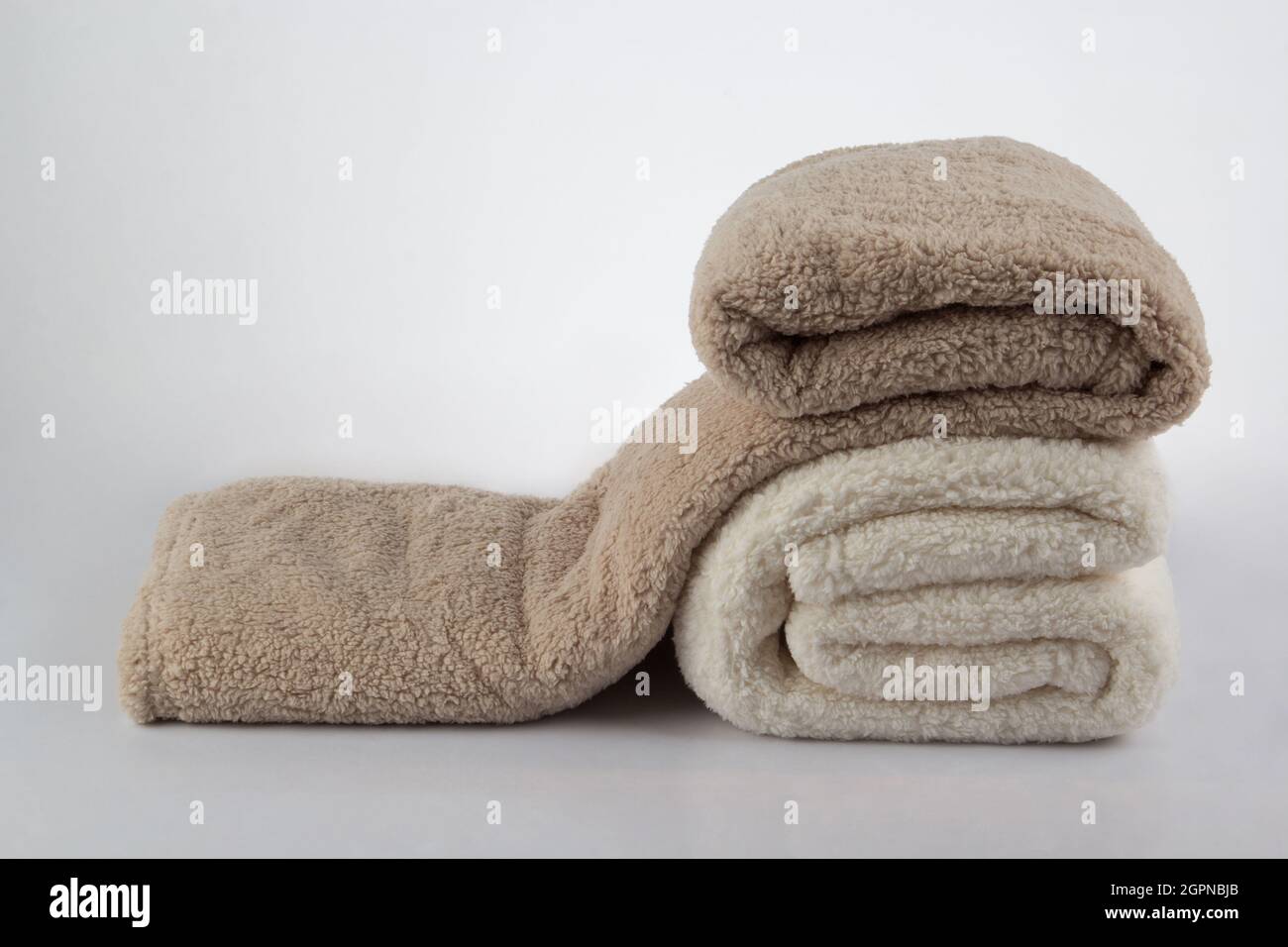 Weicher und warmer Stapel gefalteter Decken, isoliert auf weißem Hintergrund Stockfoto