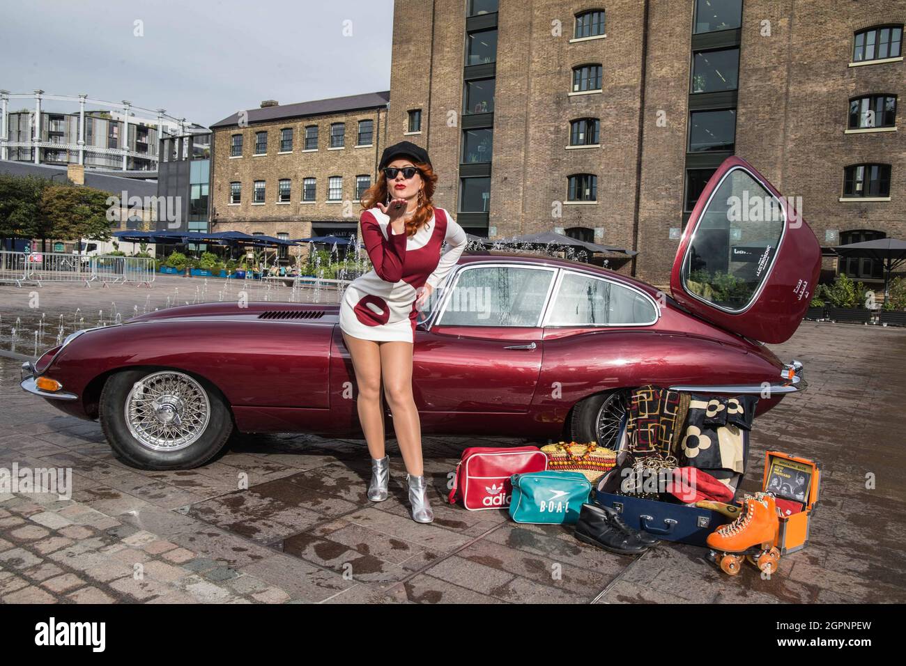 London UK 30 Sep 2021 Dressed to Impress Models posieren mit einem markanten, jetzt vollelektrischen 1967 E-Type Jag, während der Classic Car Boot Sale bei King’s Cross für seine Rückkehr am 9-10. Oktober ansteht. Das von Enzo Ferrari selbst als „das schönste Auto der Welt“ bezeichnete Fahrzeug ist eines von wenigen vollelektrischen Oldtimern dieser Art, die von Electrogenic LTD umgebaut wurden. Diese unglaubliche Fahrt ist eines der vielen Oldtimer, die diesen Oktober auf dem Festival zu sehen sind. Und Besucher können sich auf Melodien, Schmuckstücke, Paul Quezada-Neiman freuen Stockfoto