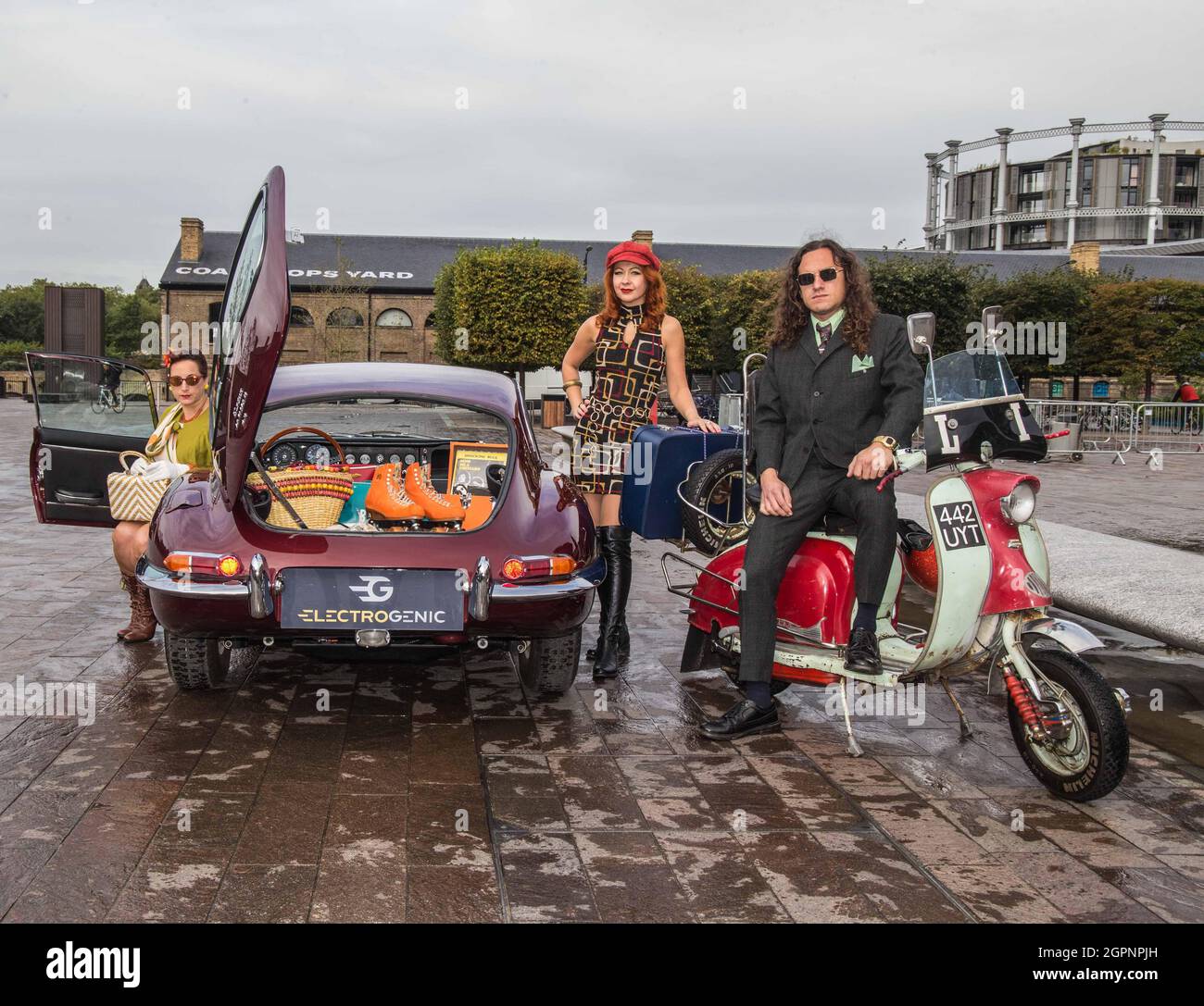 London UK 30 Sep 2021 Dressed to Impress Models posieren mit einem markanten, jetzt vollelektrischen 1967 E-Type Jag, während der Classic Car Boot Sale bei King’s Cross für seine Rückkehr am 9-10. Oktober ansteht. Das von Enzo Ferrari selbst als „das schönste Auto der Welt“ bezeichnete Fahrzeug ist eines von wenigen vollelektrischen Oldtimern dieser Art, die von Electrogenic LTD umgebaut wurden. Diese unglaubliche Fahrt ist eines der vielen Oldtimer, die diesen Oktober auf dem Festival zu sehen sind. Und Besucher können sich auf Melodien, Schmuckstücke, Paul Quezada-Neiman freuen Stockfoto