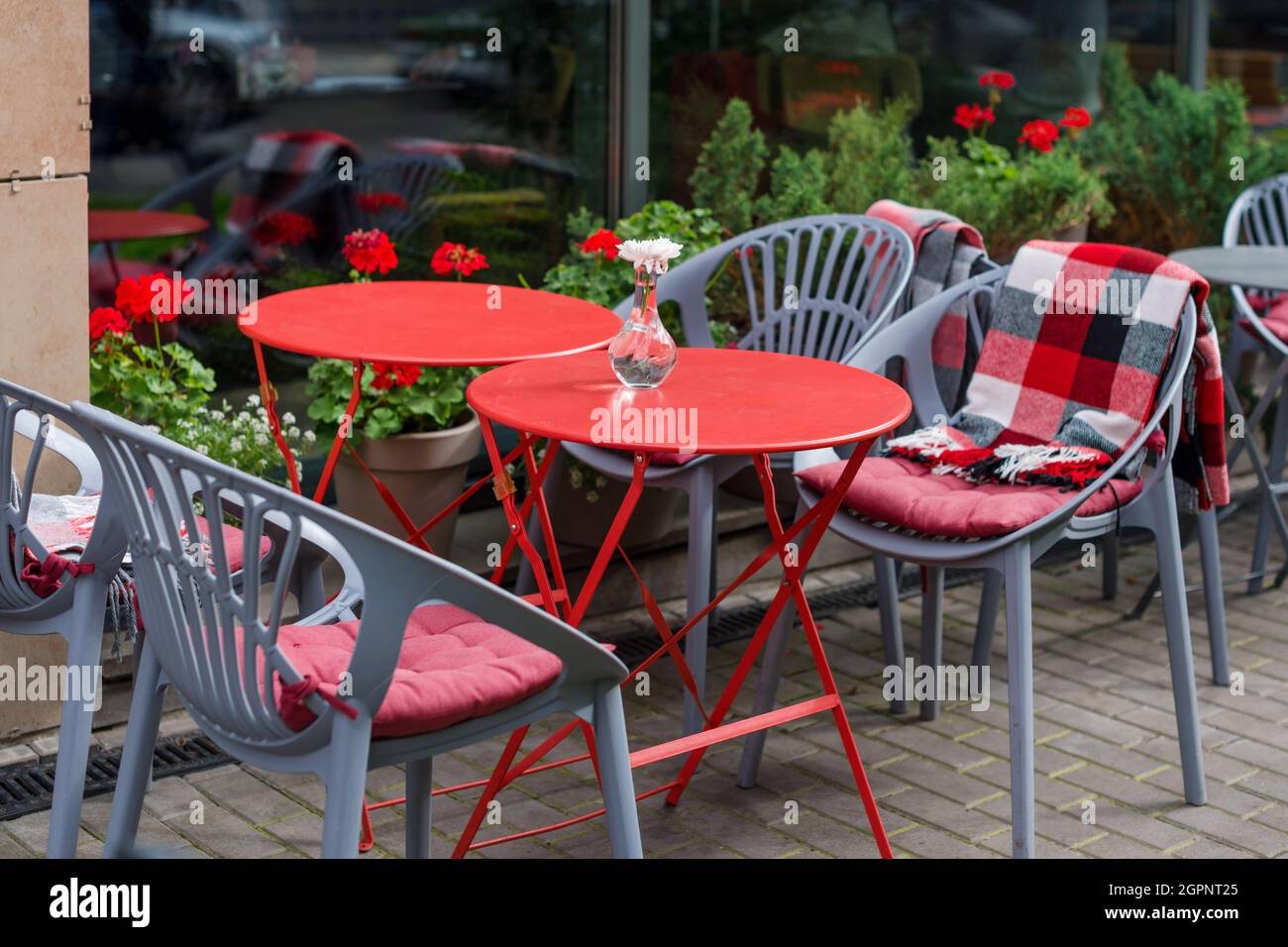 Leere Stühle im Café oder Restaurant im Freien. Tische und Stühle aus rotem  und grauem Metall im Straßencafé. Herbst in der Stadt, Plaids auf Stühlen  und Tischen von A Stockfotografie - Alamy