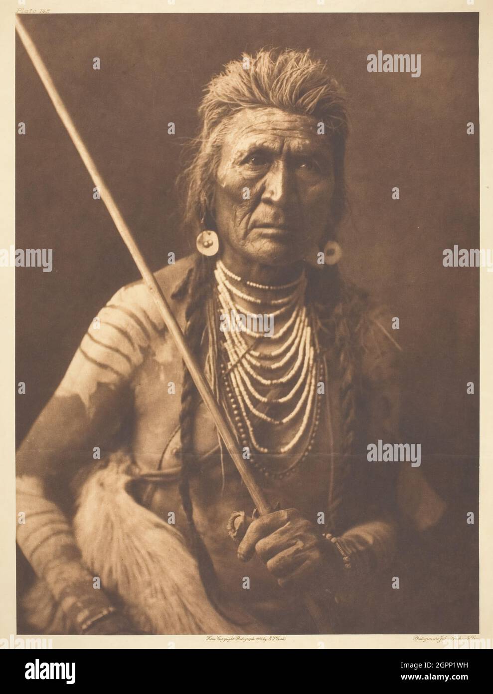 Wolf - Apsaroke, 1908. [Amerikanischer Ureinwohner aus dem Nordwesten der Vereinigten Staaten, mit Muschelketten und Körperfarbe]. Photogravure, Platte 142 aus „The North American Indian, Band 4“ (1909). Stockfoto