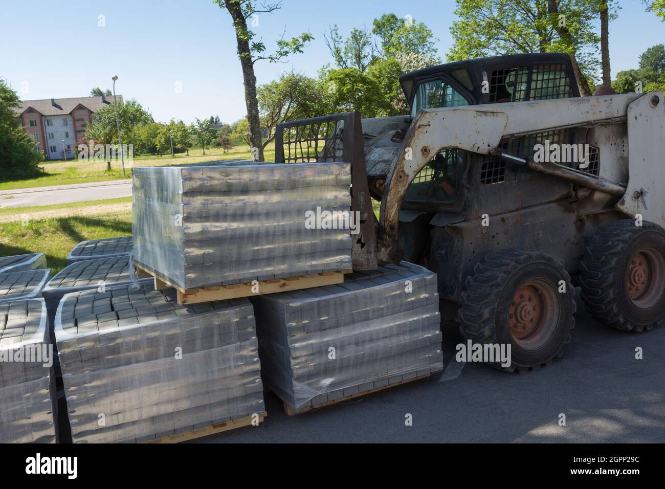 Der Traktor hebt eine Palette mit Betonsteinen an Stockfoto