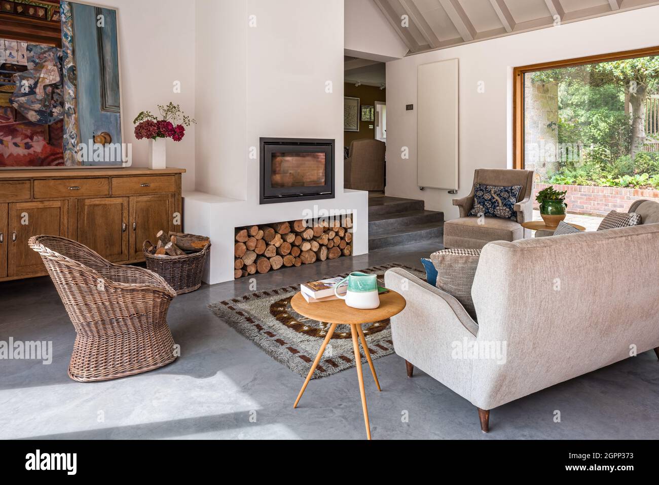 Sofa aus der Mitte des Jahrhunderts mit Korbstuhl in Sussex Bauernhaus, Großbritannien Stockfoto