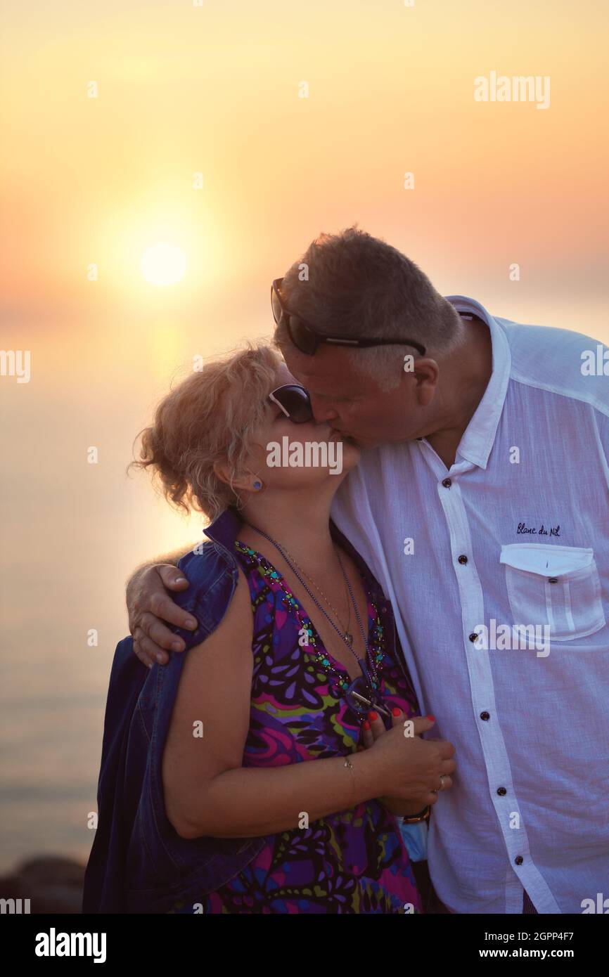 Zärtlicher und romantischer Kuss eines älteren Paares während des Sonnenuntergangs Stockfoto