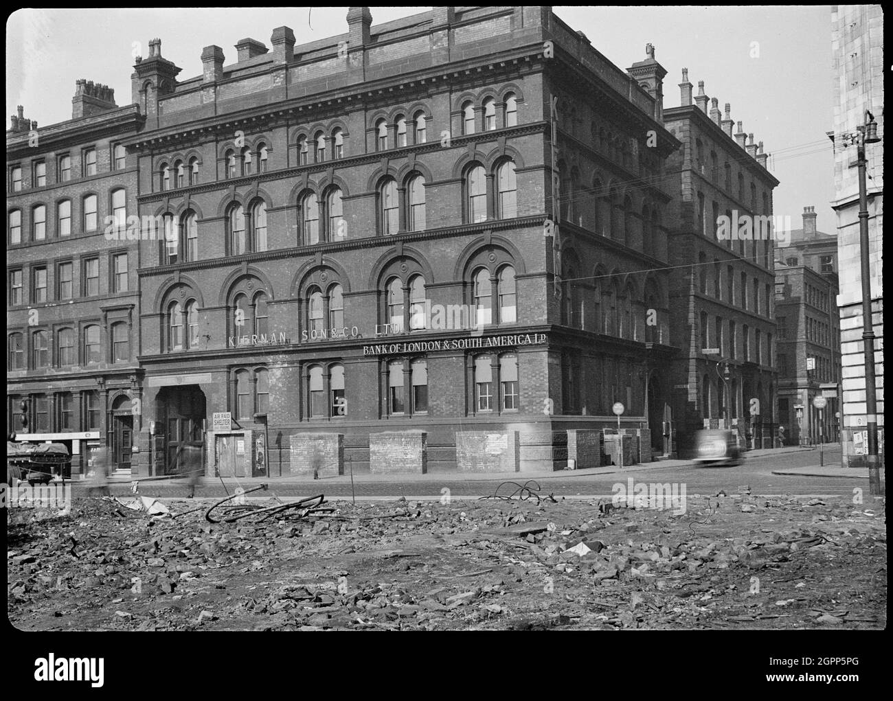 Fraser House, Charlotte Street, Manchester, 1942. Außenansicht von Fraser House, einem ehemaligen Lagerhaus an der Ecke Charlotte Street und Portland Street, von Süden aus gesehen, mit Schutt im Vordergrund. Das Lager wurde zwischen 1855 und 1860 von Edward Walters mit roten Backstein- und Sandsteinauflagen erbaut und als Lager eines Textilherstellers genutzt. Es hat vier Stockwerke und einen Keller, mit fünf Buchten im Süden und drei Buchten im Osten. An der Südfassade steht ein Schild mit der Aufschrift: "AIR RAID SHELTER/ 200 PERSONS", und im Vordergrund sind Schutt, höchstwahrscheinlich Bombe Stockfoto