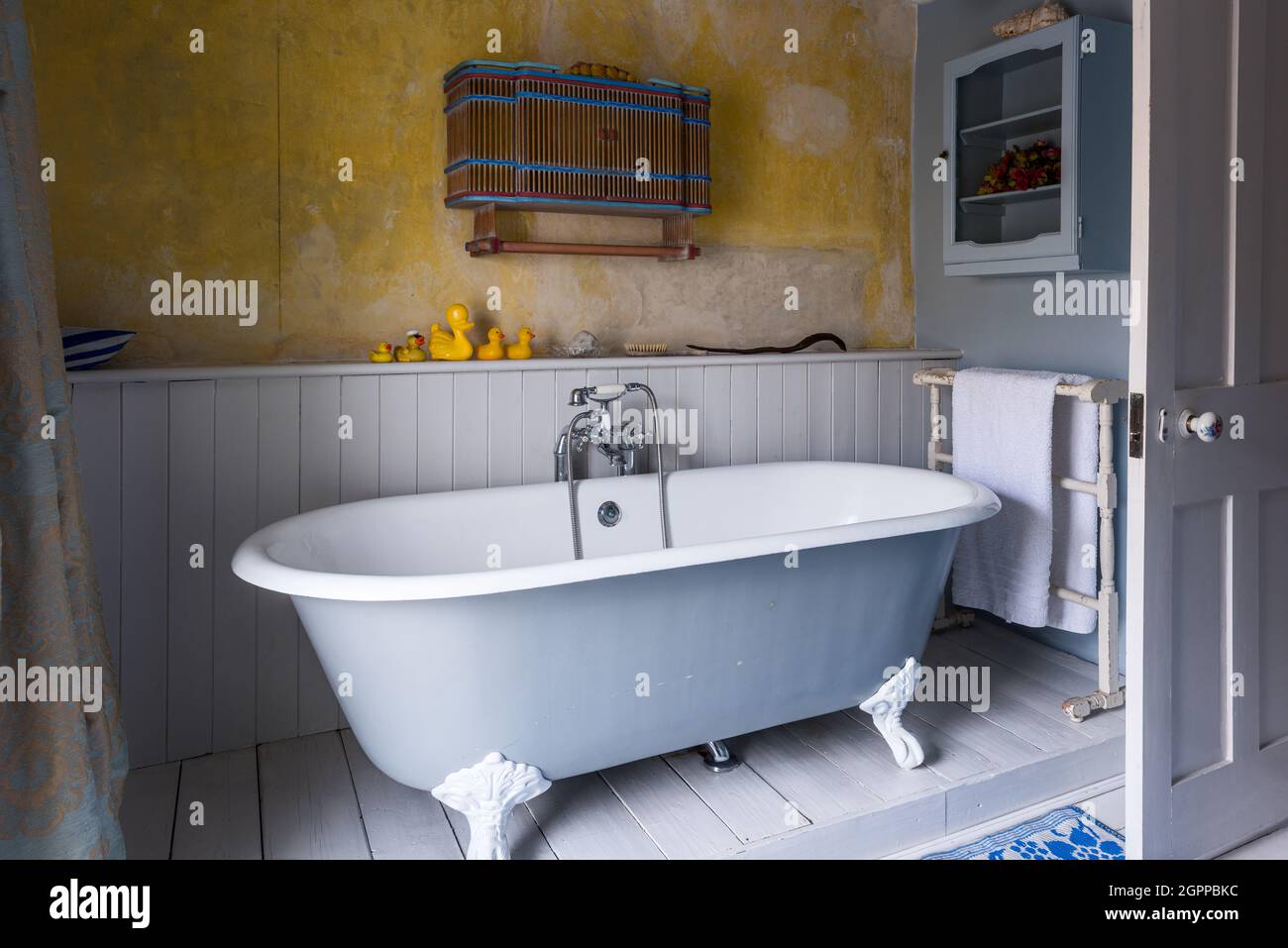 Wandschrank und Gummienten mit freistehender Badewanne in Suffolk Cottage. Stockfoto