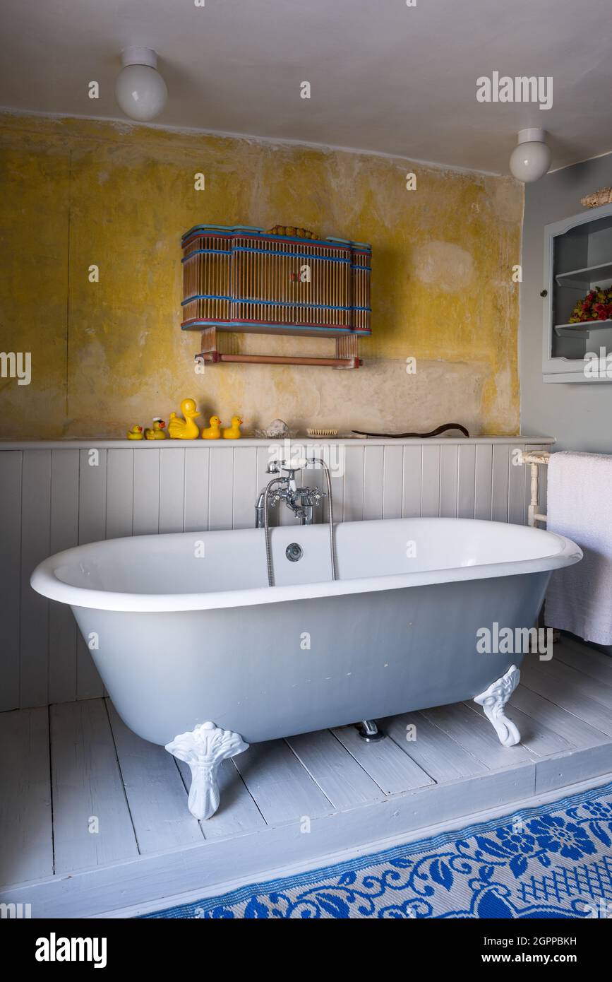 Wandschrank und Gummienten mit freistehender Badewanne in Suffolk Cottage. Stockfoto