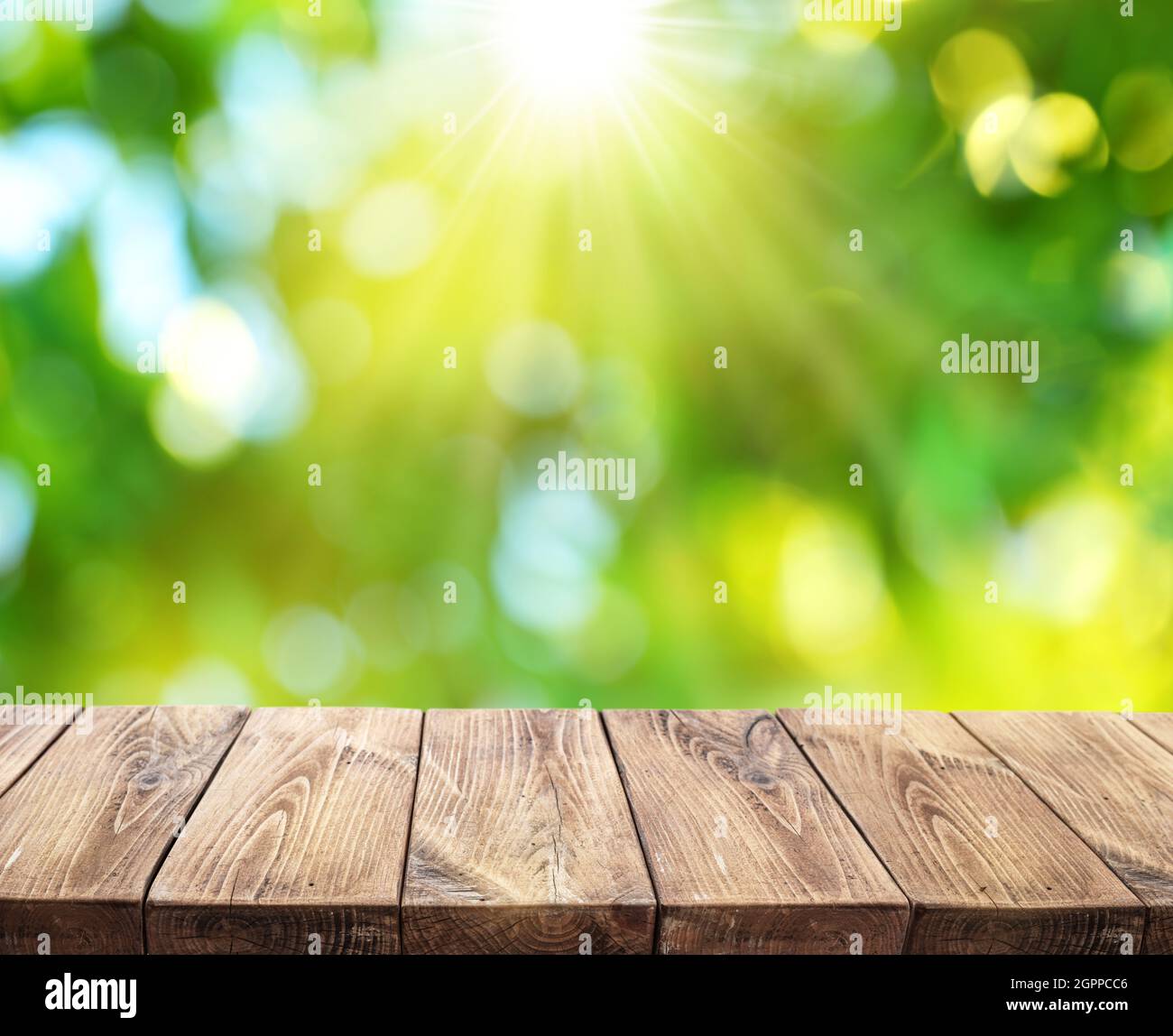 Bokeh sonnige Natur Hintergrund und Holzbrett im Vordergrund. Die Datei enthält den Beschneidungspfad der Platine. Es ist möglich, Ihr Produkt zu platzieren. Stockfoto
