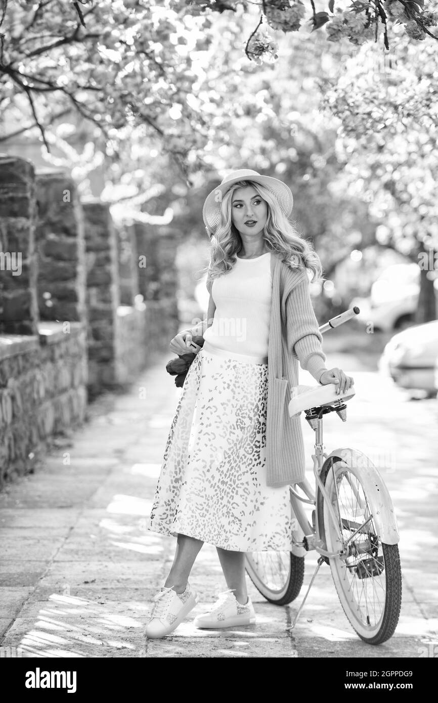 Die Schönheit der Kirsche. Jung und sorglos. Mädchen Blumenverkäufer mit Retro-Fahrrad. Vintage-Fahrrad für einen angenehmen Spaziergang im Park. Mode Frau genießen Frühling Natur Stockfoto