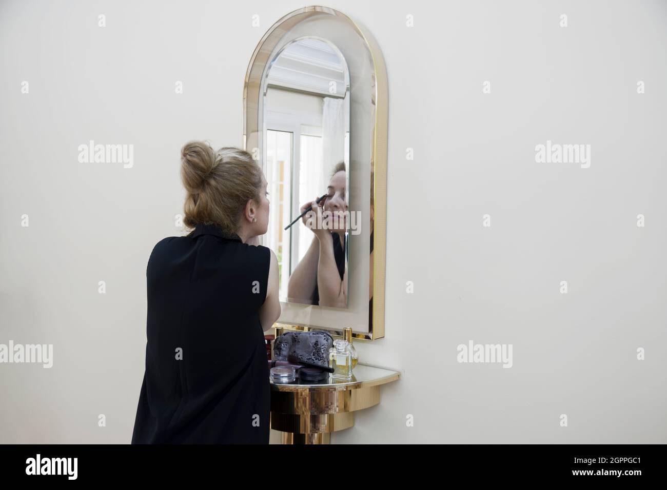 Junge Frau macht Make-up vor dem Spiegel. Sich auf einen wichtigen Tag vorbereiten Stockfoto