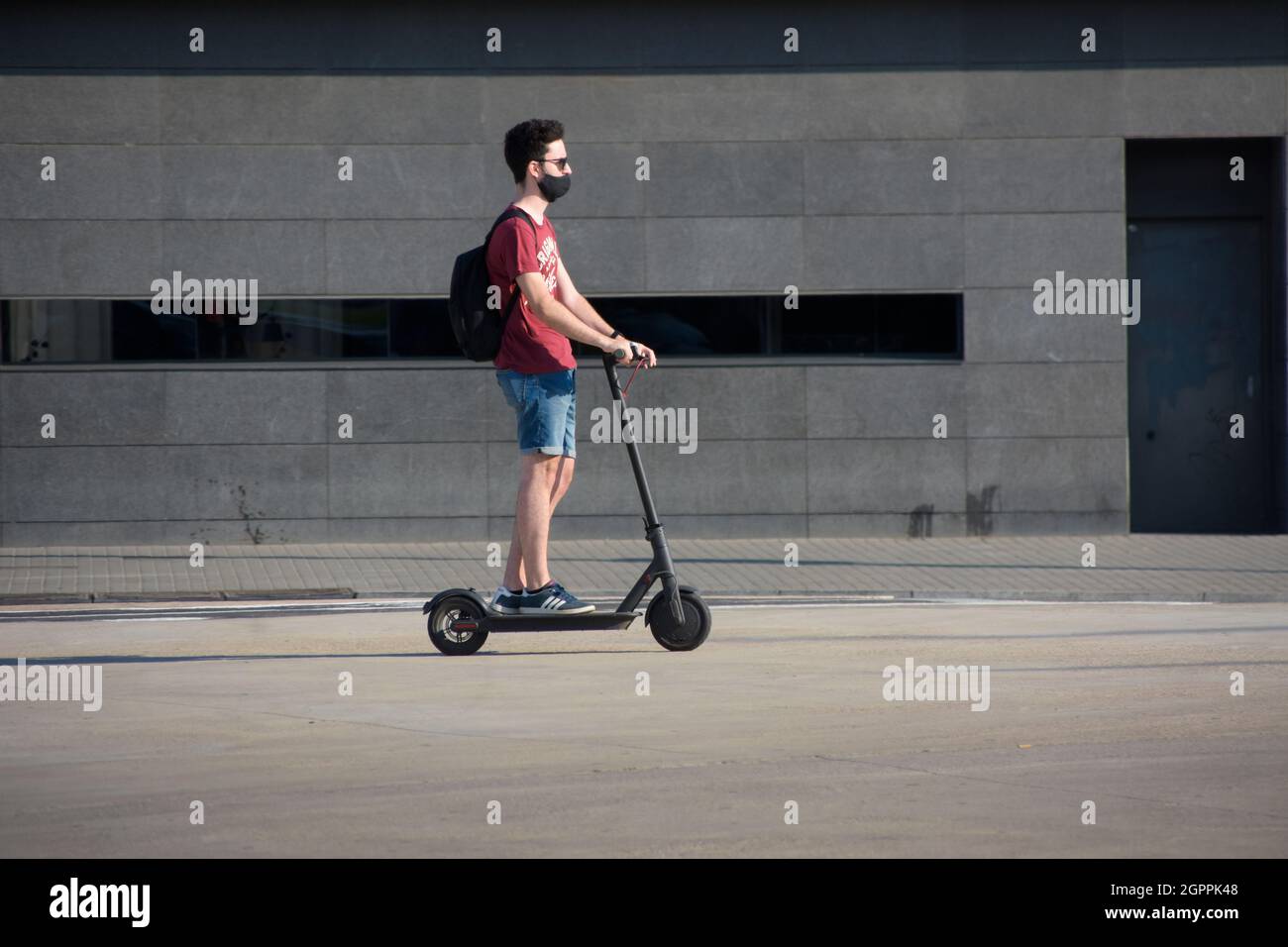 Junger Mann, der auf einem Elektroroller auf einer Straße reitet. Stockfoto
