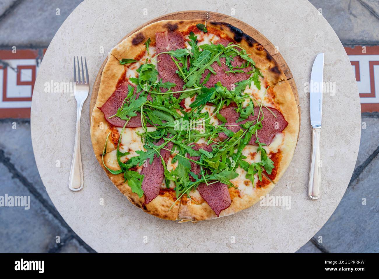 Pizza in Scheiben mit Parmaschinken und Oragula auf einem weißen Teller.Snack im St. Regis Hotel, Nursultan Kasachstan Stockfoto