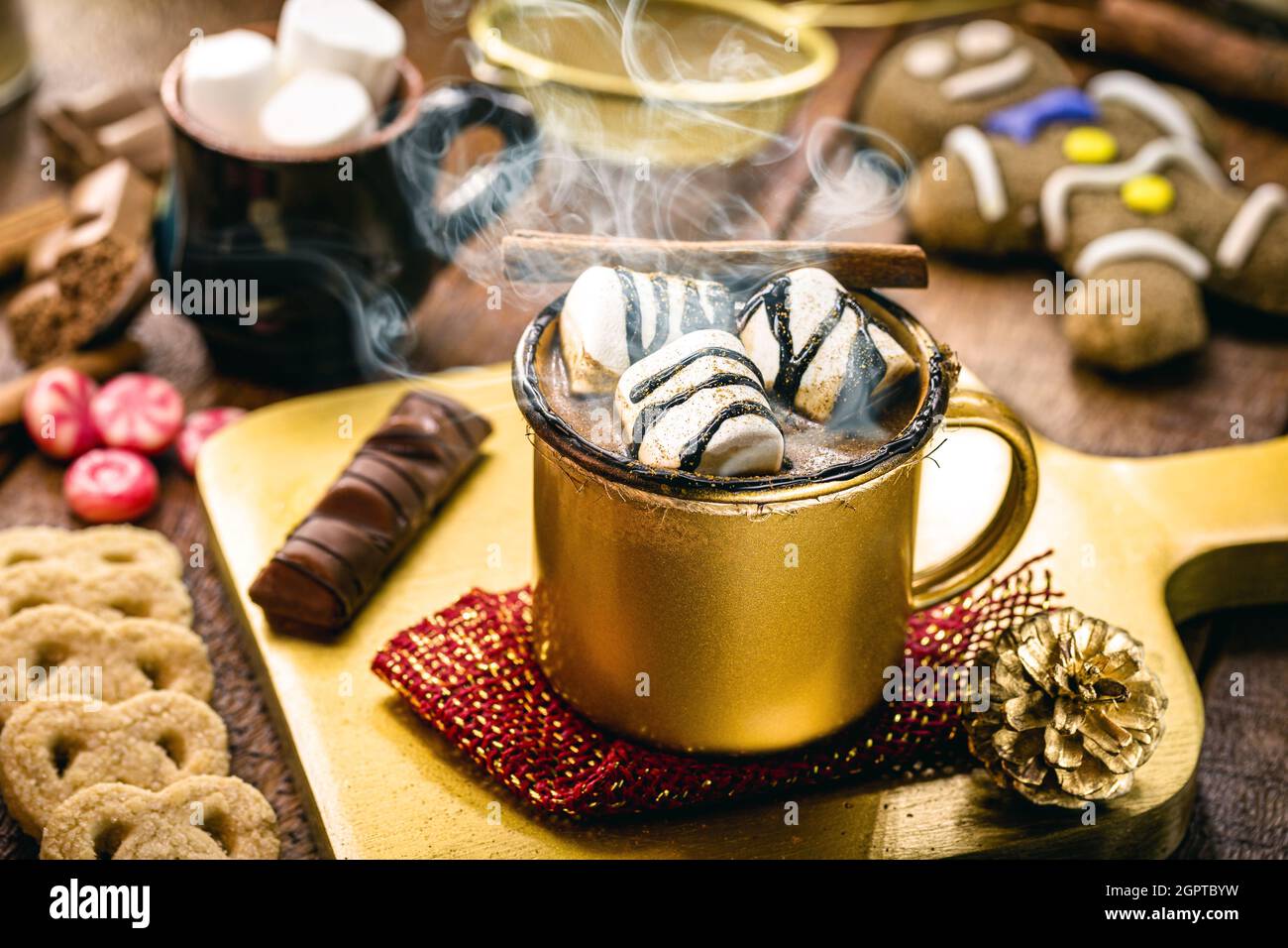 Heiße Schokolade mit Marschmalchen, Dampf oder Rauch, hausgemachtes Weihnachtsgetränk, mit Lebkuchenmann im Hintergrund Stockfoto