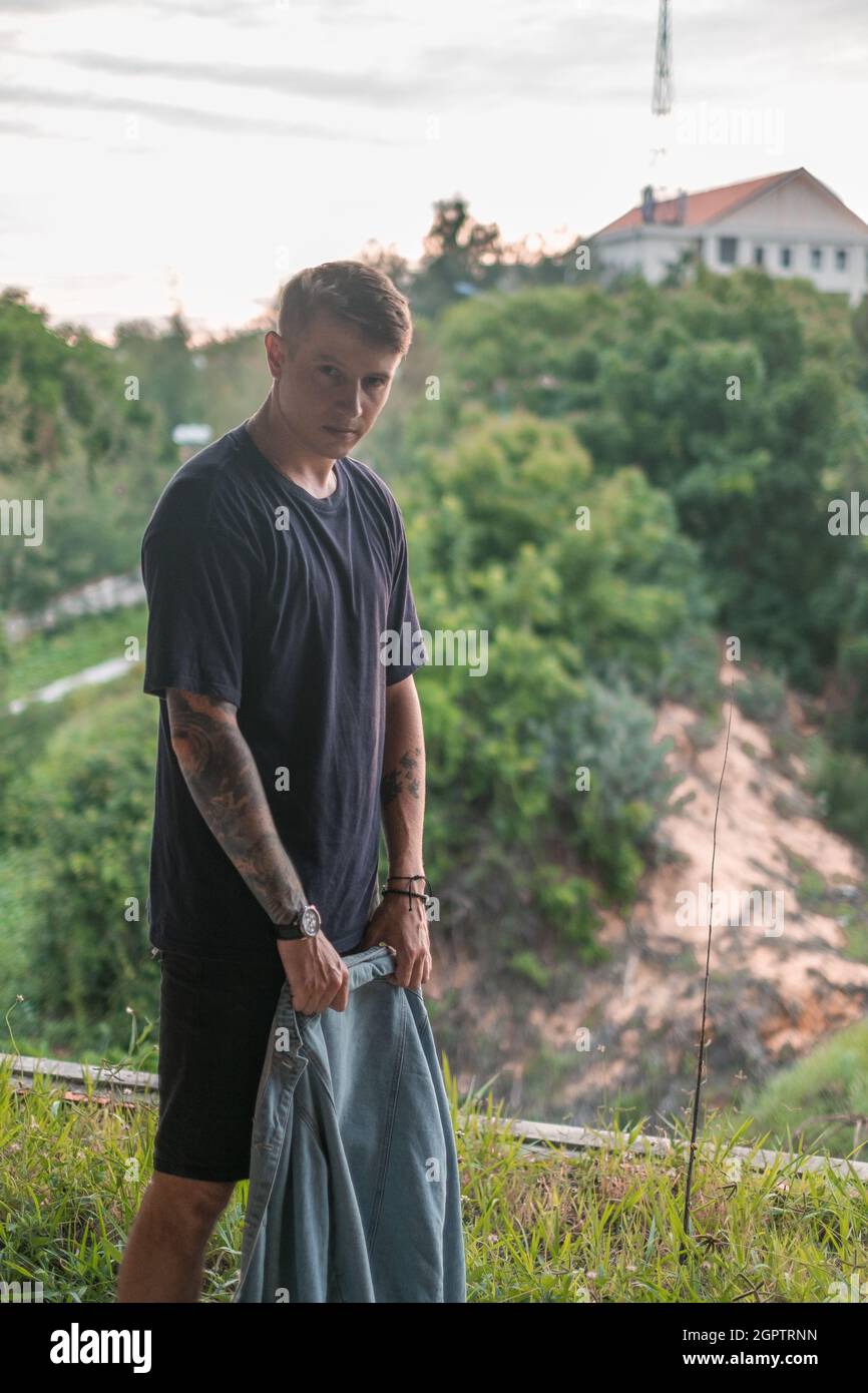 Porträt eines jungen, gutaussehenden kaukasischen Mannes mit Full-Arm-Tattoo in legerem Tragegefühl, beim Gehen und beim Betrachen der Kamera mit Kopierraum. Wütender ernster Blick Stockfoto