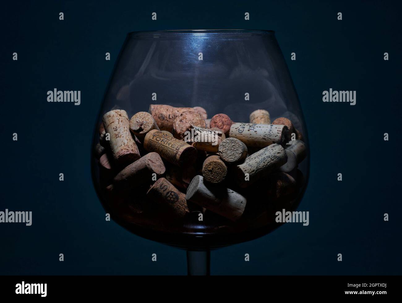 LA HABANA, KUBA - 31. Aug 2021: Ein großes transparentes Glas mit vielen Weinflaschen Korken auf blauem Hintergrund Stockfoto
