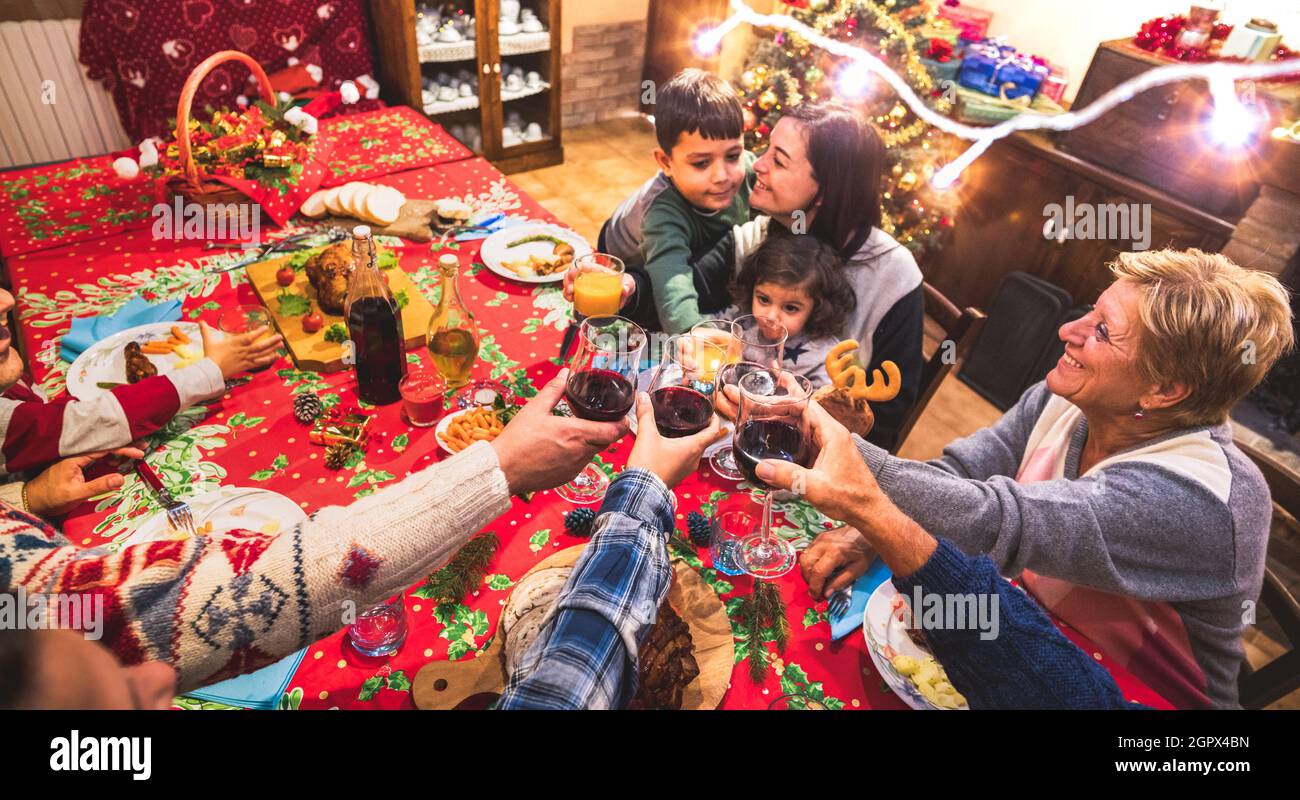 Fröhliche, mehrjährige Familie, die sich auf der weihnachtsabendessen-Party amüsieren kann - Silvesterstimmung mit Rotweingläsern in der Gruppe - Winterurlaub-Konzept Stockfoto