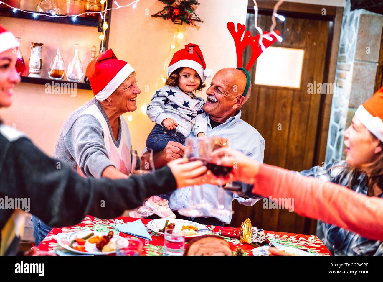 Multi-Generation-Familie mit Spaß auf Weihnachtsessen Party - Winterurlaub Weihnachten Konzept mit Großeltern und Tochter zusammen essen Eröffnungsgeschenk Stockfoto