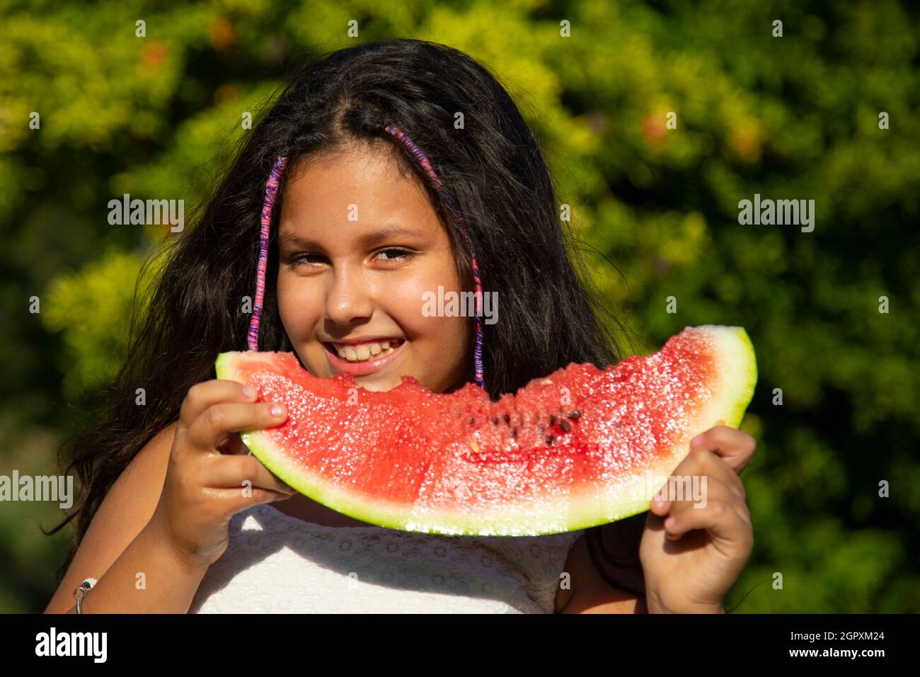 gypsy Mädchen mit langen schwarzen Haaren isst die große Scheibe Wassermelone Stockfoto