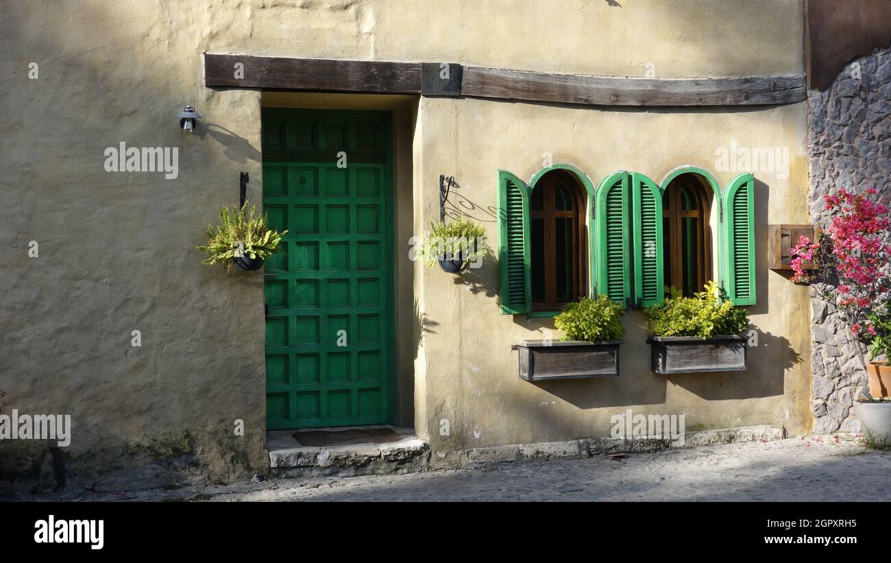 Die Vorderseite des Hauses mit Blumen und Holztüren und Fenstern in grüner Farbe gemalt Stockfoto