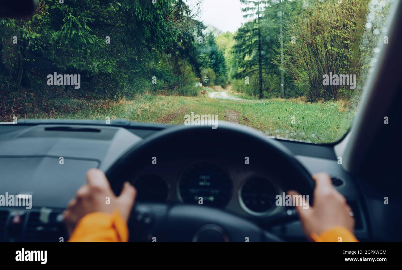 Fahrer gekleidet leuchtend orange Jacke fahren eine moderne Offroad-Rechtslenker RHD Auto auf dem Berg grünen Wald Landstraße. POV im Auto Winde Stockfoto