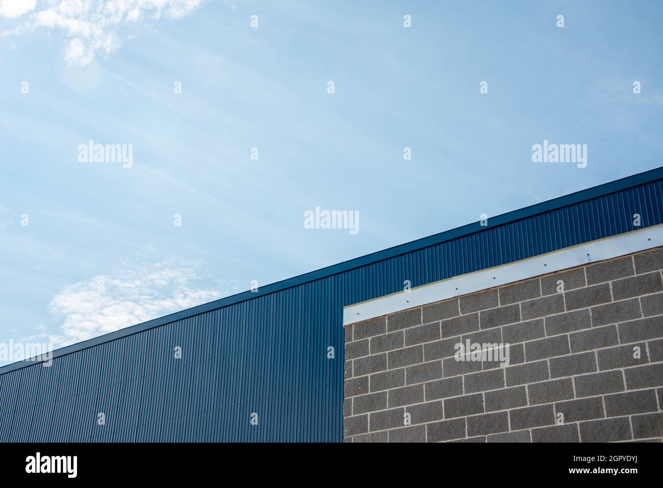 Die Außenwand eines Geschäftsgebäudes mit grauem Ziegelstein, hellgrauem Mörtel und silberfarbenem Blinken oder Faszien. Die Wand ist tiefblaues Blech Stockfoto