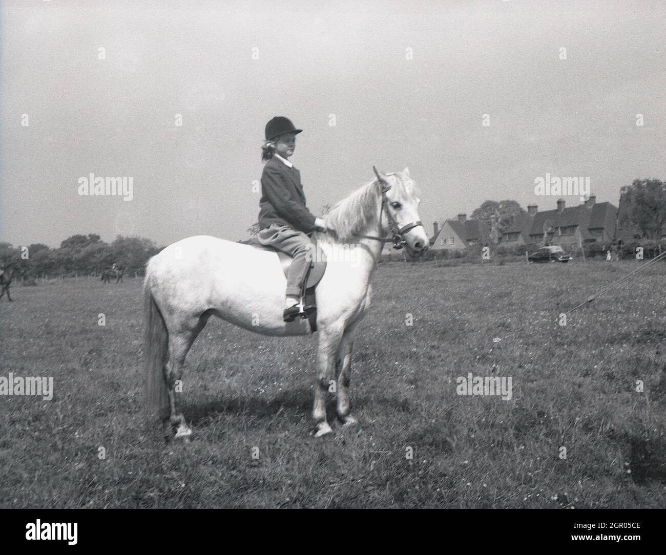 In den 1950er Jahren, historisch, draußen auf einem großen, offenen Feld, sitzt eine junge Reiterin auf ihrem Pferd bei einem Wettkampfwettbewerb, Sussex, England, Großbritannien. Stockfoto