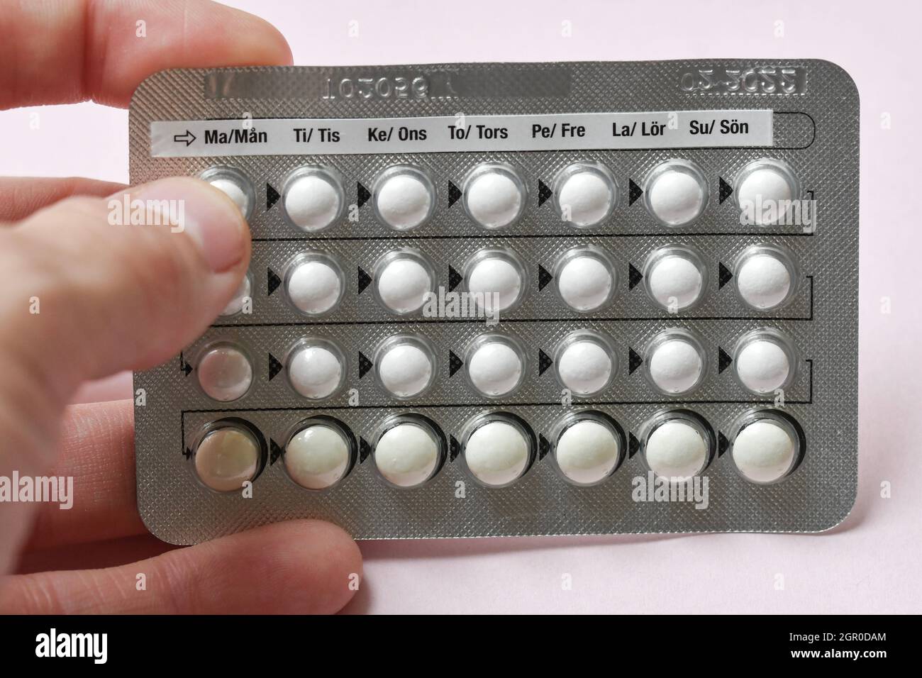 Eine Frau, die eine vollständige Tabelle der Geburtenkontrolle Pillen auf rosa Hintergrund hält Stockfoto