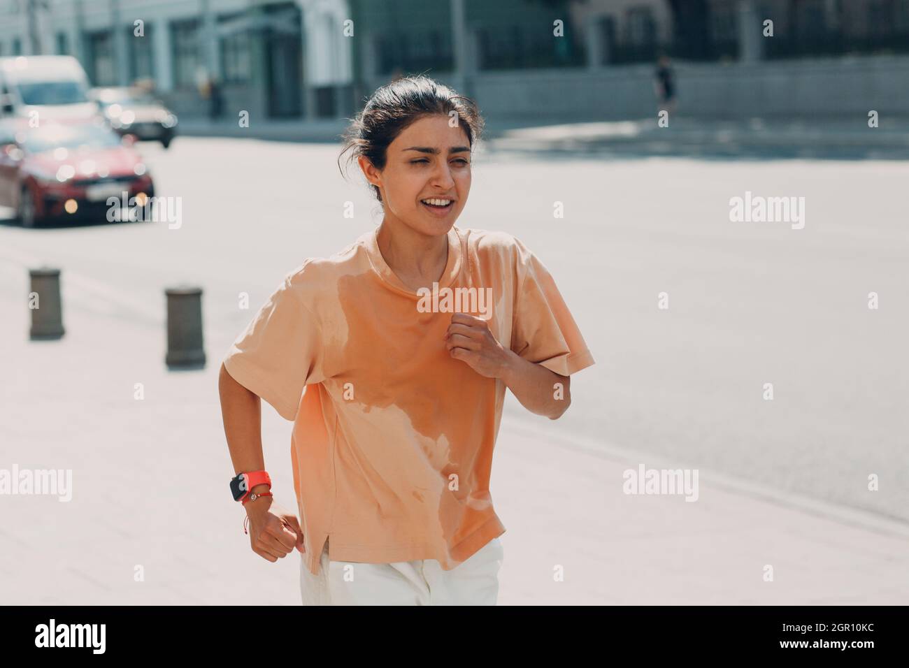 Junge indische Läuferin joggt in nassem, schweißtreibendem T-Shirt auf der City Street Urban Stockfoto