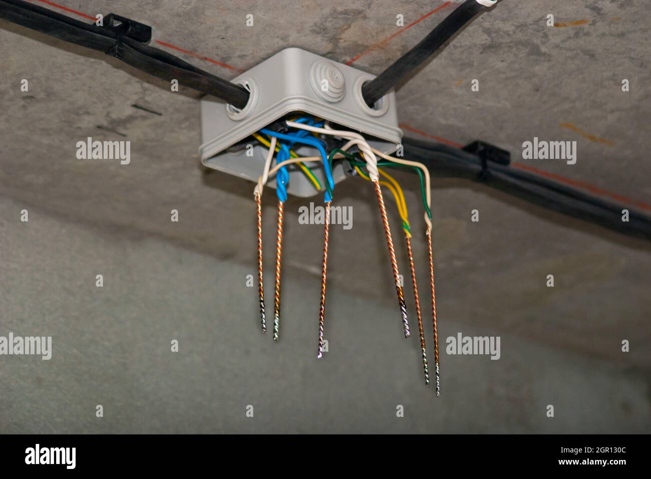 Offene Anschlussdose mit verdrillten und gelöteten Elektrokabeln, die an der Decke befestigt sind Stockfoto