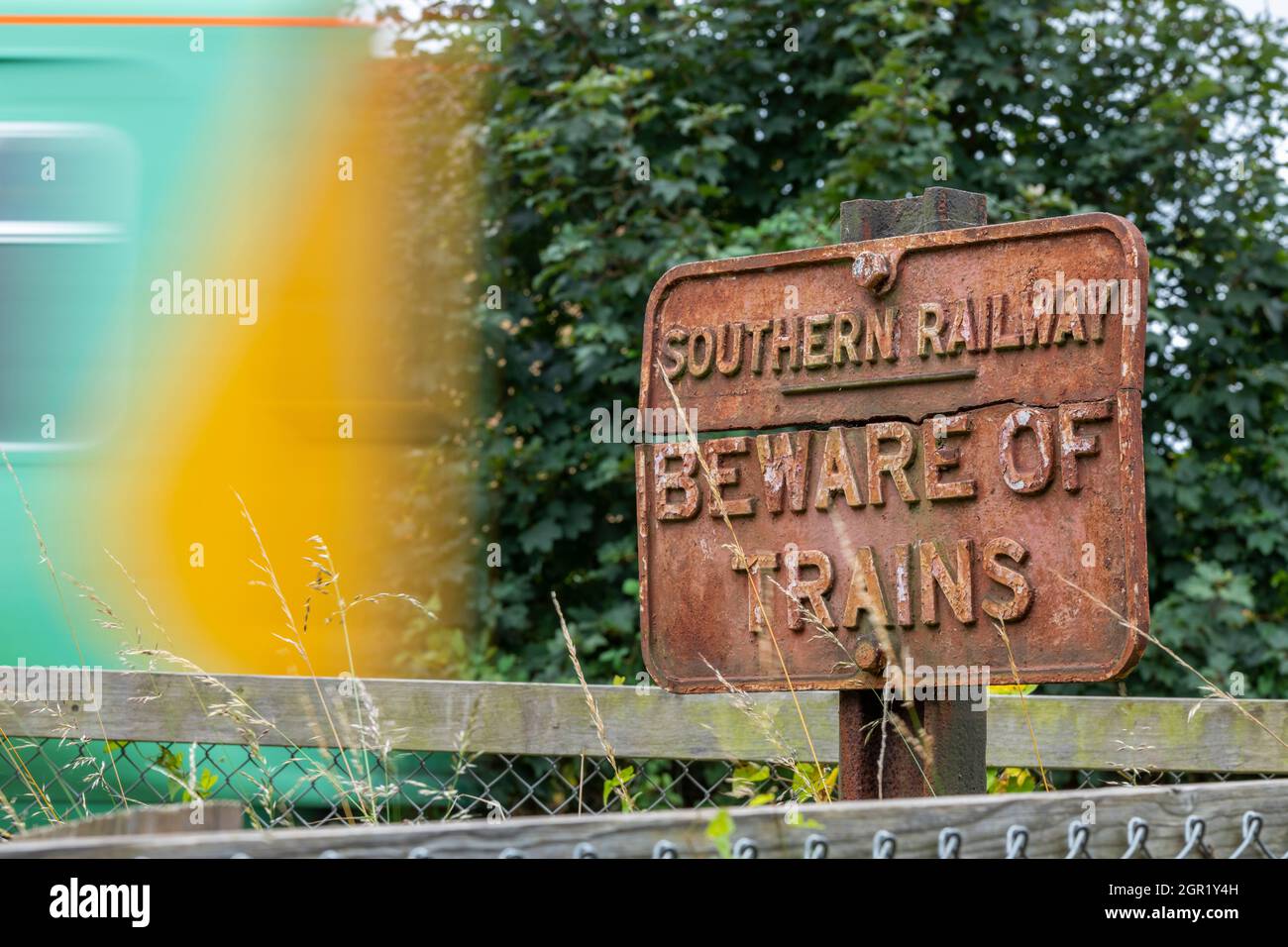 Vintage südlichen Eisenbahn Gusseisen Zeichen hüten sich vor Zügen mit einem verschwommenen schnellen Zug in südlichen Schiene Lackierung mit Geschwindigkeit. Southern Railway TOC. Stockfoto