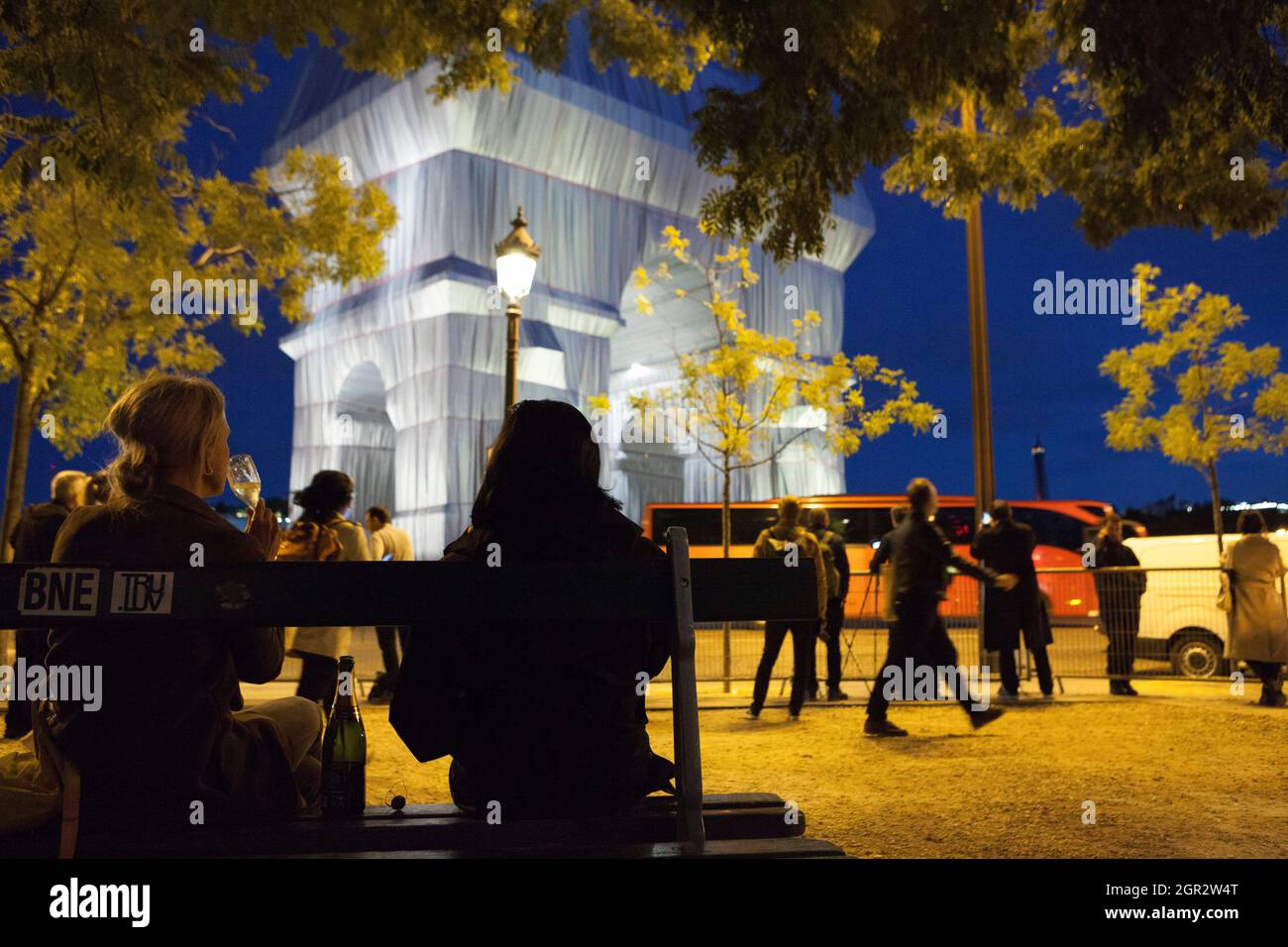 Paris, Frankreich, 30. September 2021: Der Arc de Triomphe in Paris, wie von den Künstlern Christo und Jeanne-Claude geplant in Silbergewebe gewickelt, zieht einen stetigen Strom von Touristen an, darunter zwei Frauen, die eine Flasche Champagner auf einer Bank teilen. An diesem Wochenende wird der Place Charles de Gaulle, der den Bogen umgibt, für den Verkehr gesperrt, was eine sicherere Sicht auf die Sehenswürdigkeiten ermöglicht als für diejenigen, die aus der Mitte der Boulevards, die vom Kreisverkehr ausstrahlen, einige Aufnahmen gemacht haben. Die Kunstinstallation wird ab Montag, dem 4. Oktober, demontiert, damit die Feierlichkeiten zum Waffenstillstandstag wie gewohnt stattfinden können. Anna Wa Stockfoto