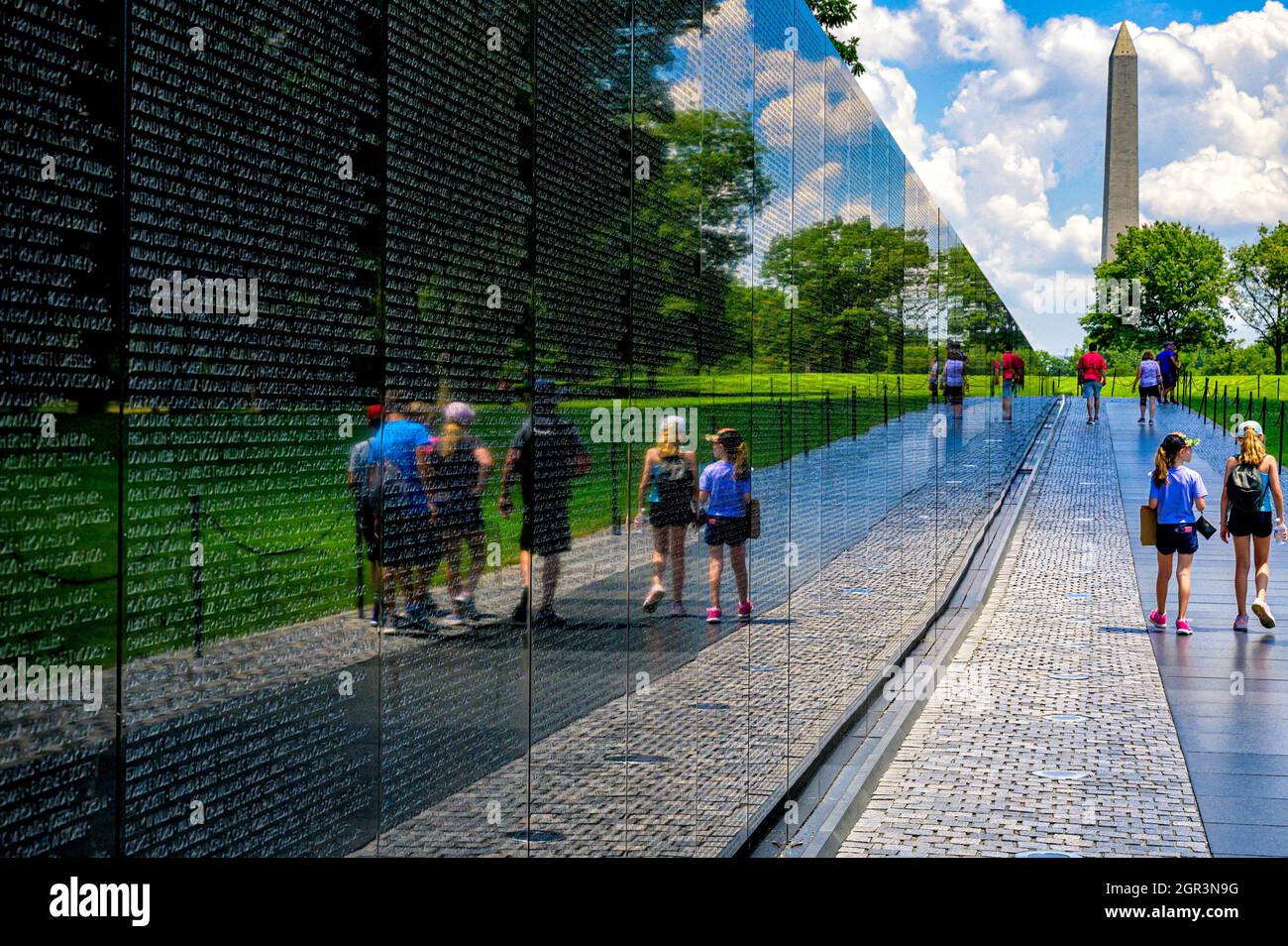 Spiegelungen an der Wand des Vietnam Veterans Memorial mit dem Washington Monument im Hintergrund Stockfoto