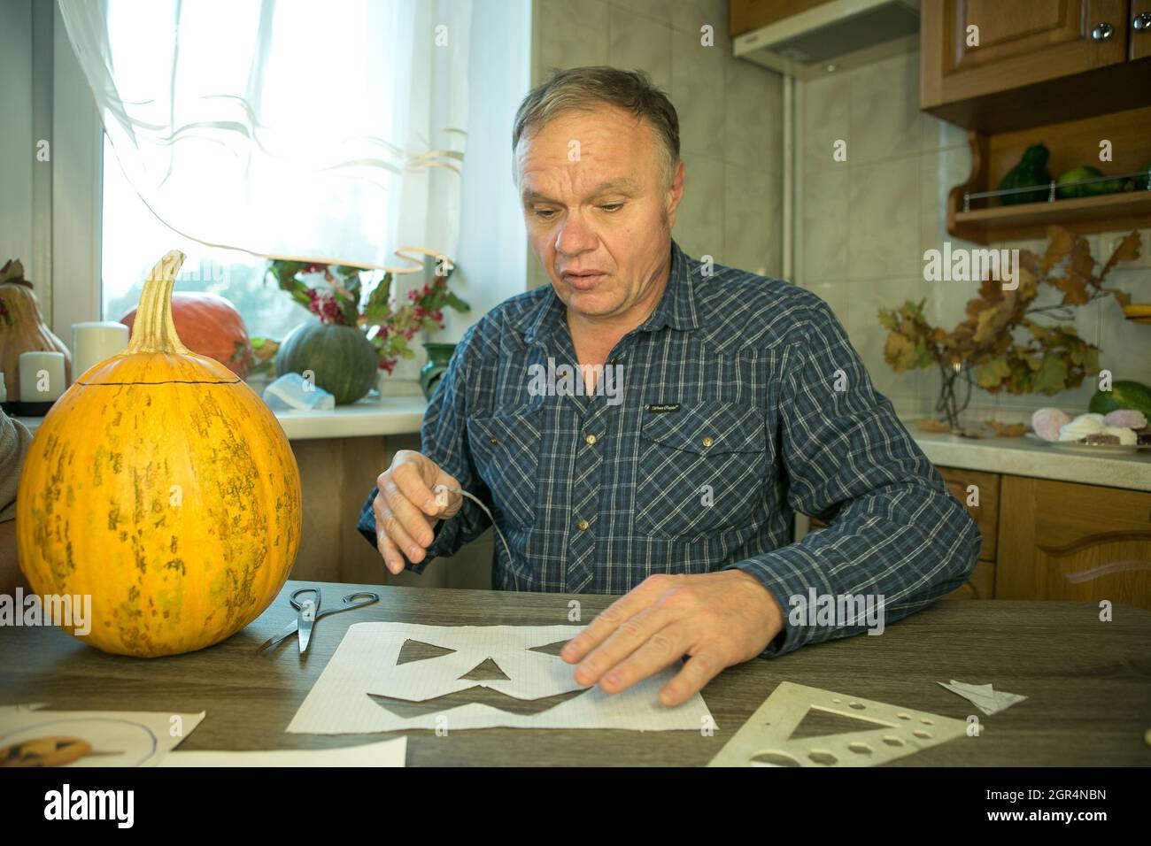 Jack O'Lantern zu Hause machen. Jack O'Lantern Thread-Vorlage erstellen Prozess. Der Mann bereitet den Kürbis zum Schnitzen vor. Stockfoto